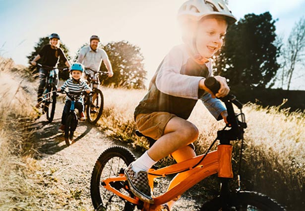 Niño andando en bicicleta con la familia siguiéndolo
